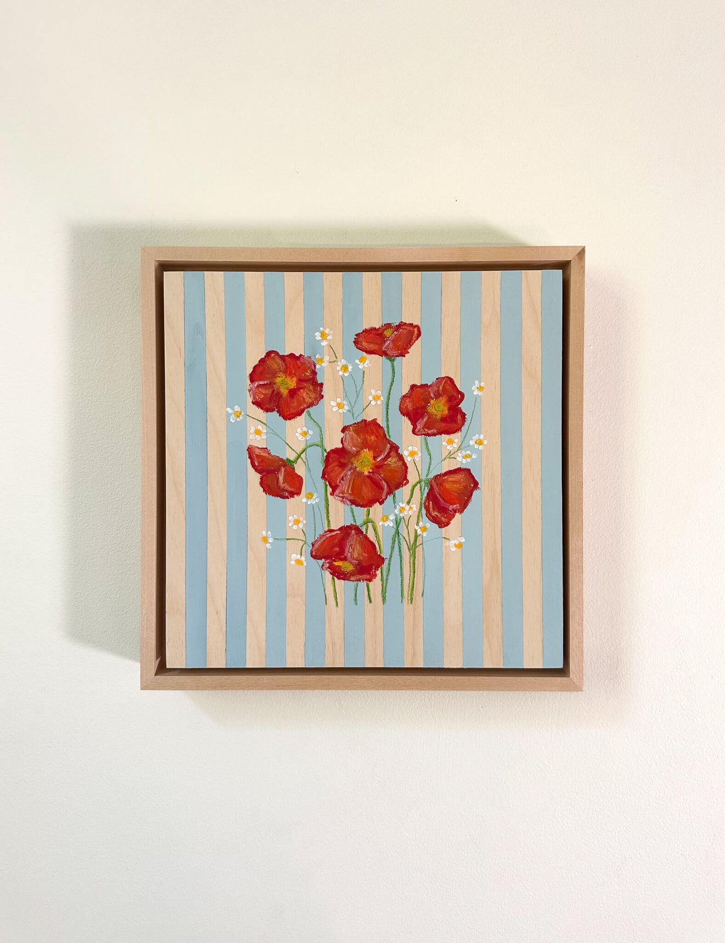 Framed artwork with red flowers on a striped background