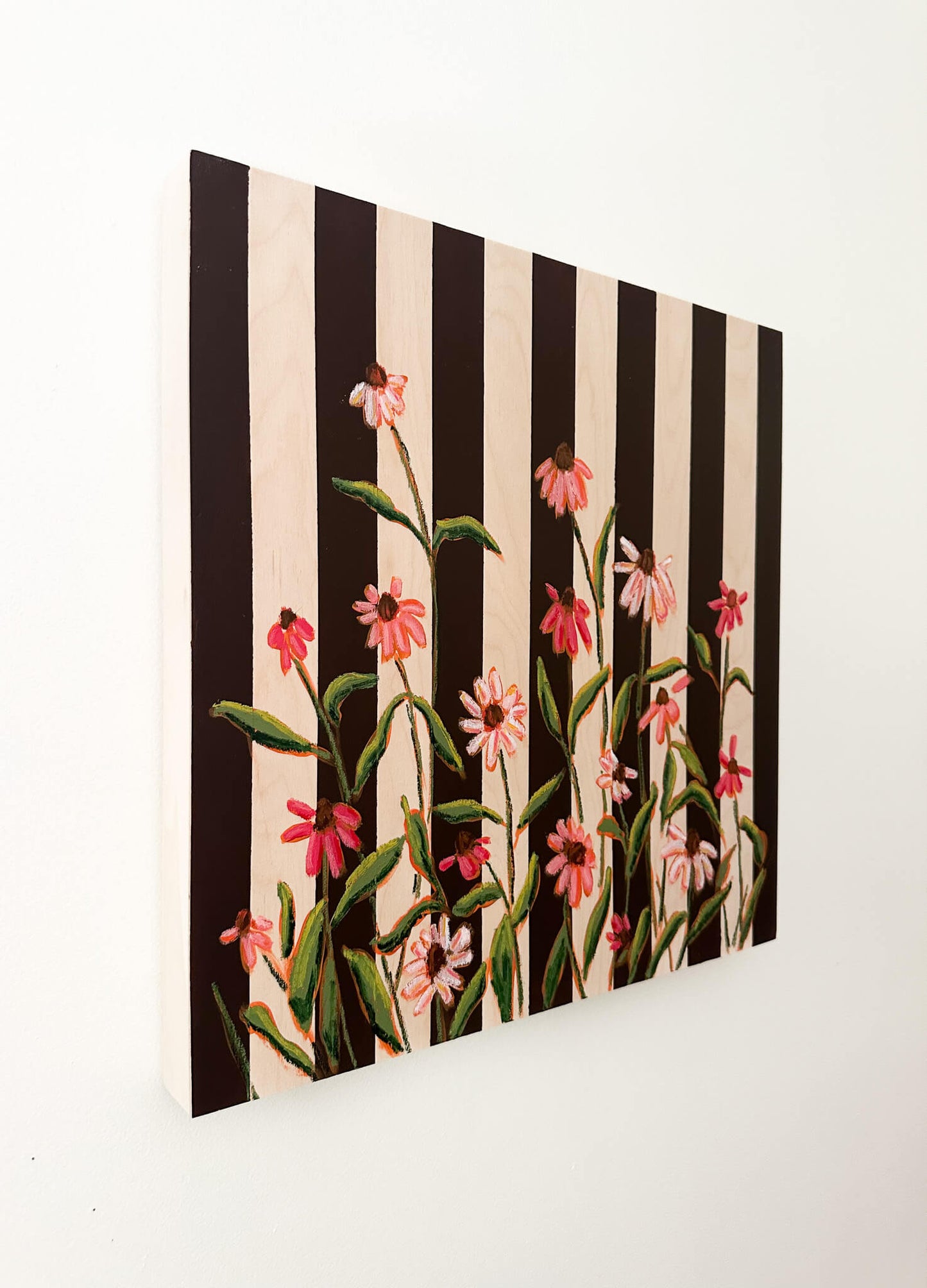 Floral pattern with pink flowers and green leaves on a black and white striped background