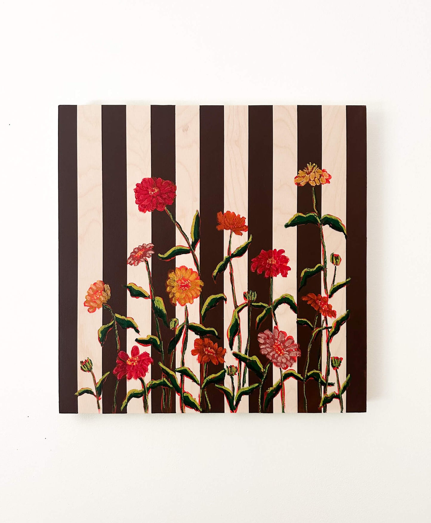 Floral artwork with black and white stripes on a white wall