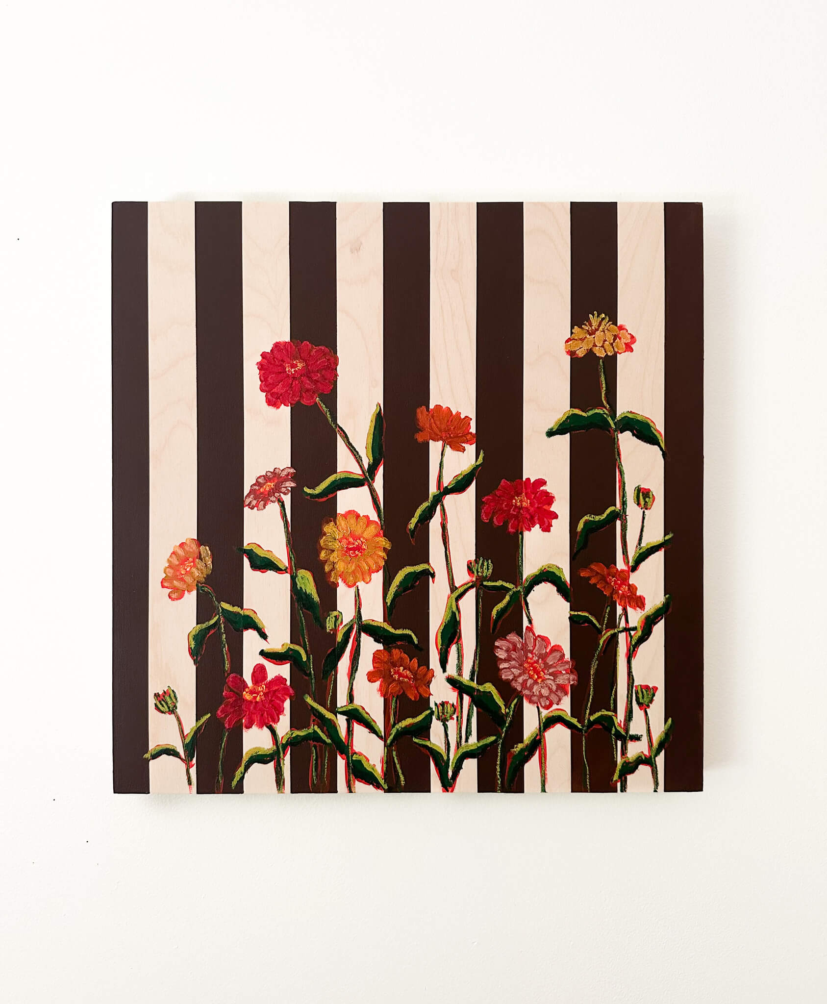 Floral artwork with black and white stripes on a white wall