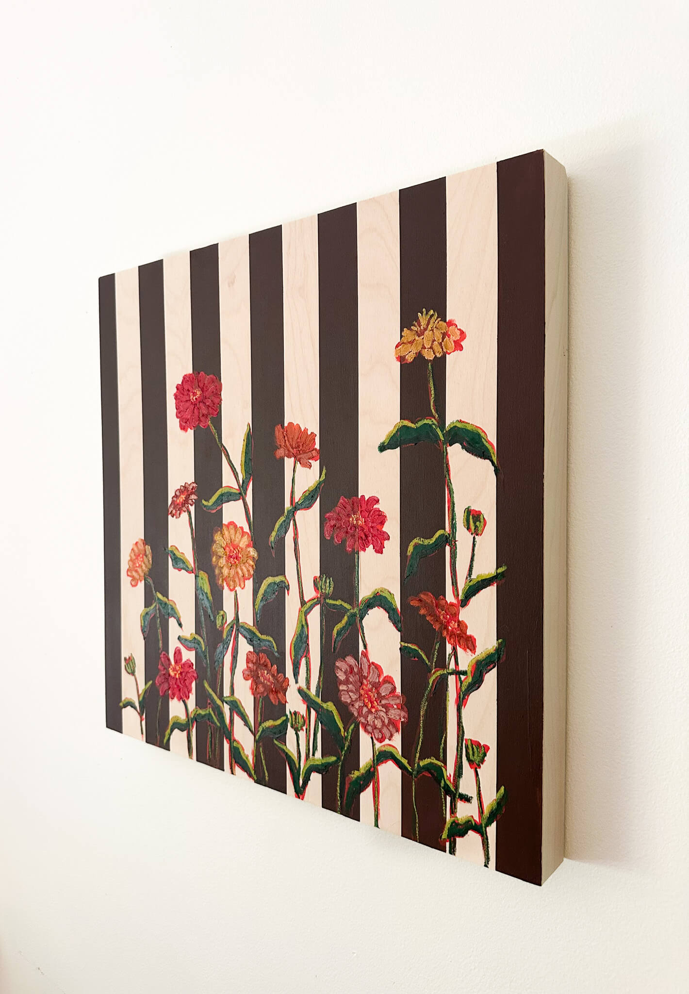 Floral artwork with black and white stripes on a white wall