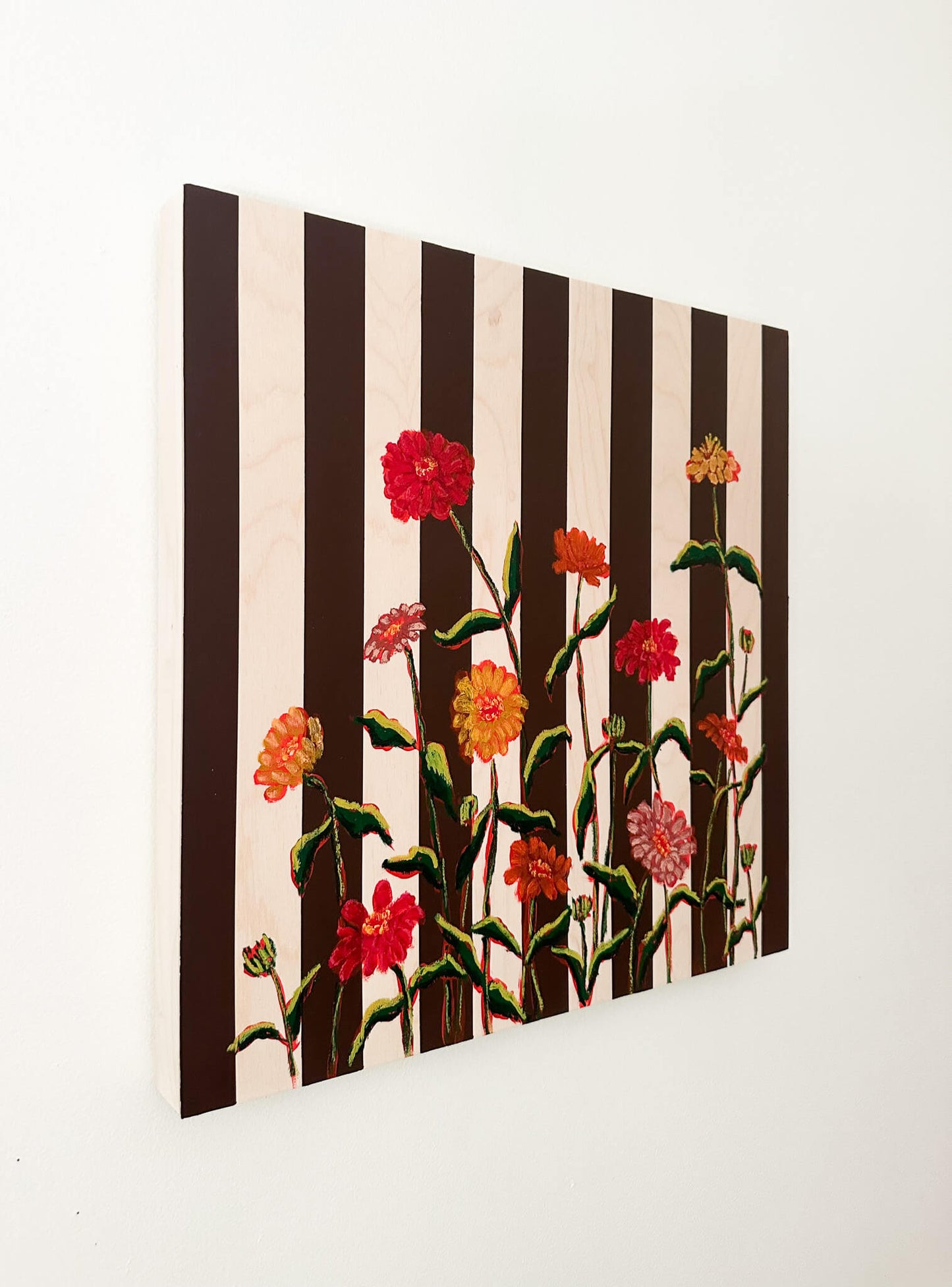 Floral artwork with black and white stripes on a white wall