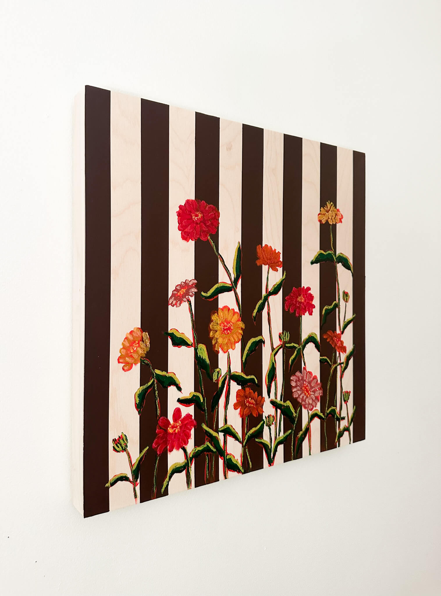 Floral artwork with black and white stripes on a white wall