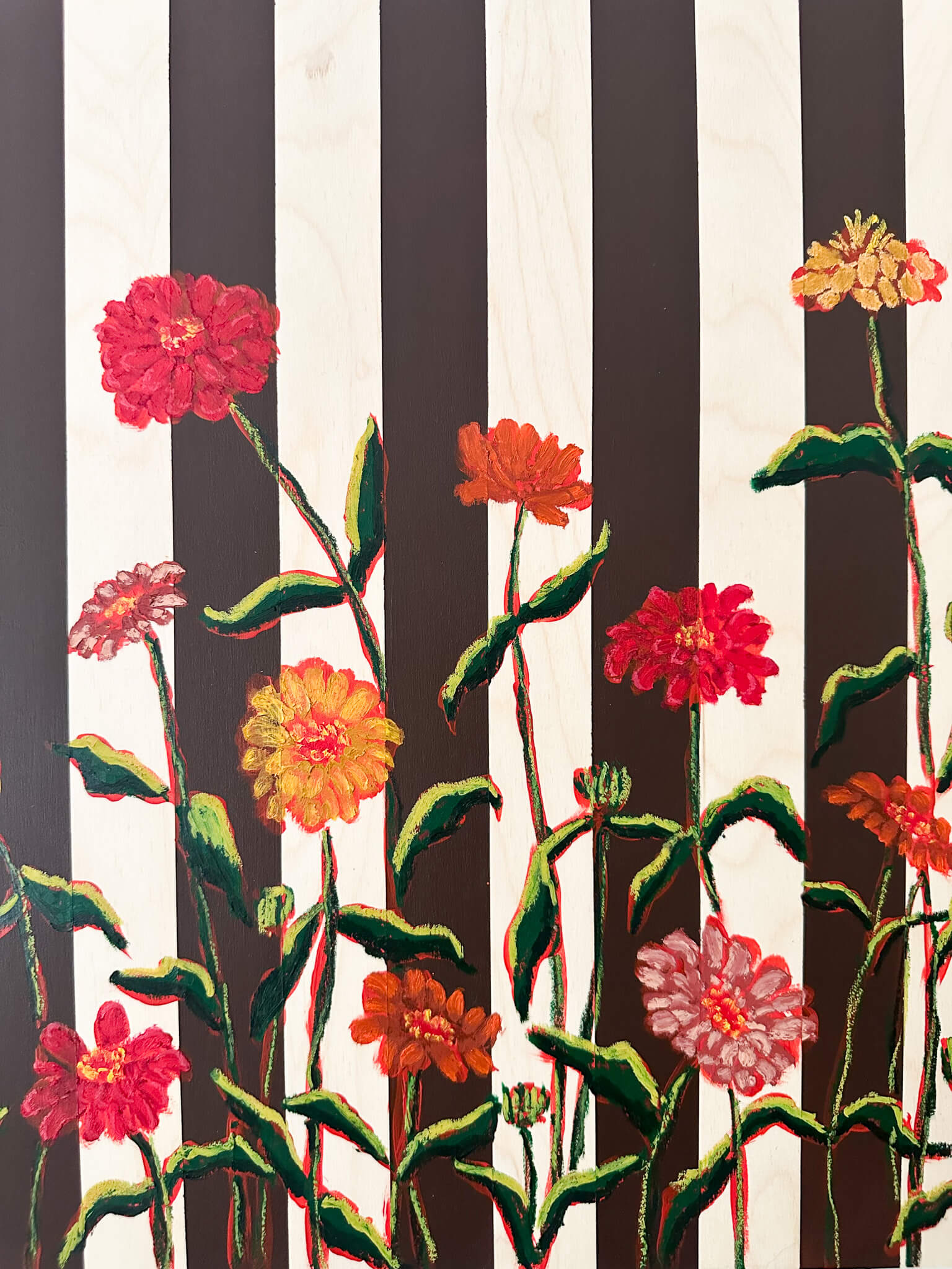 Floral artwork with black and white stripes on a white wall