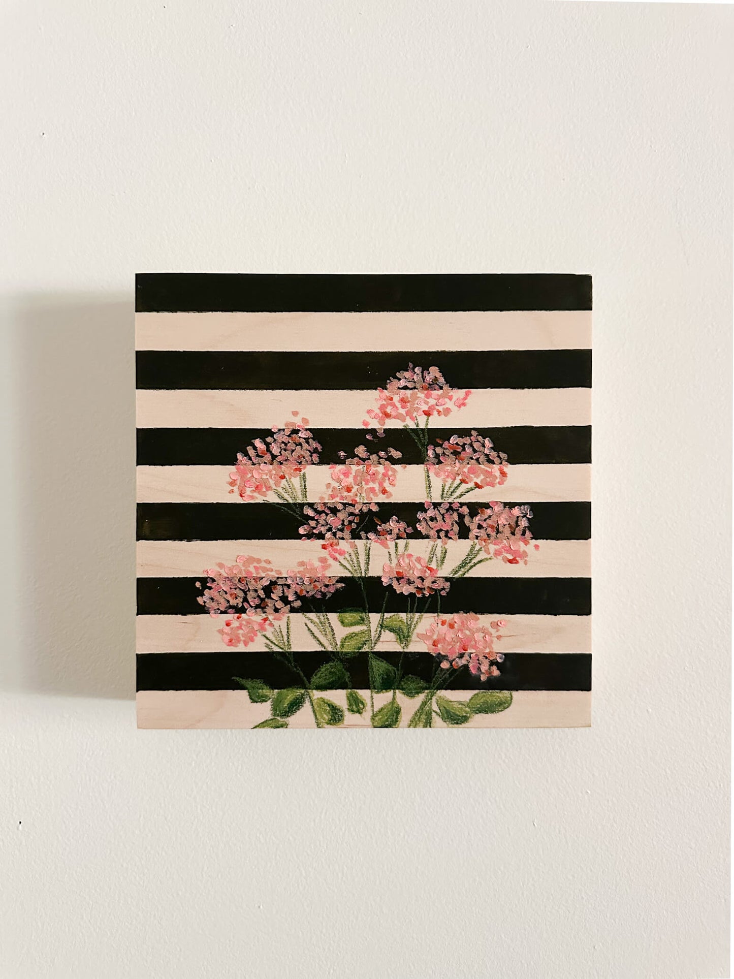 pink oil pastel florals on a very dark green and wood striped wood panel.