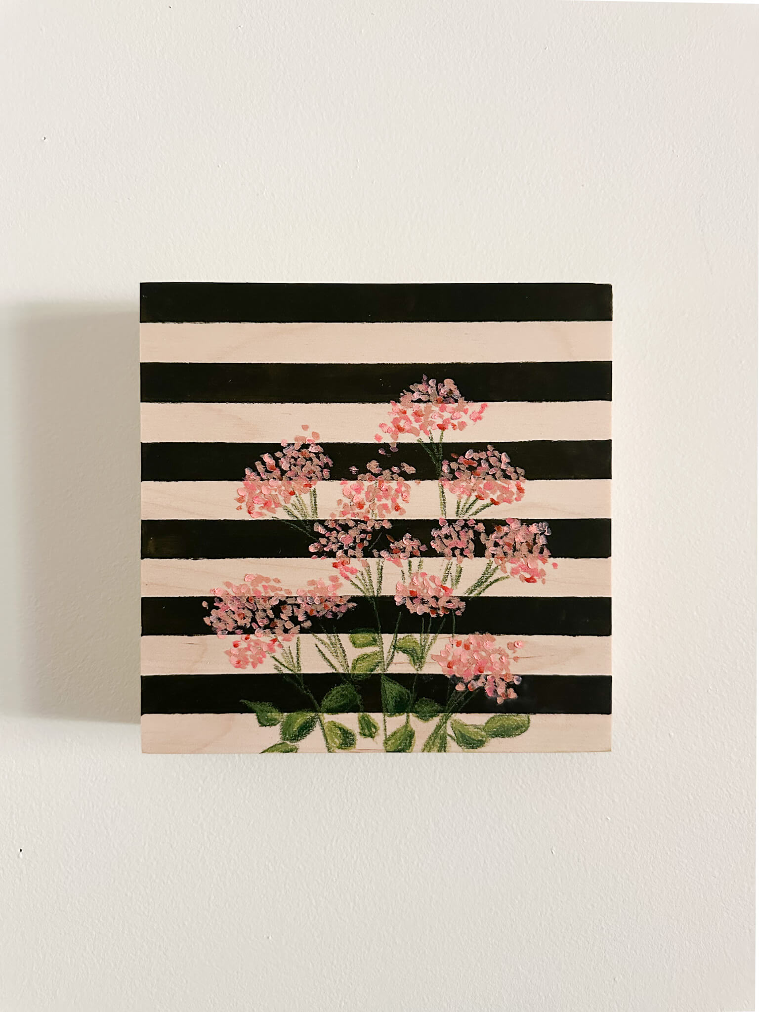 pink oil pastel florals on a very dark green and wood striped wood panel.