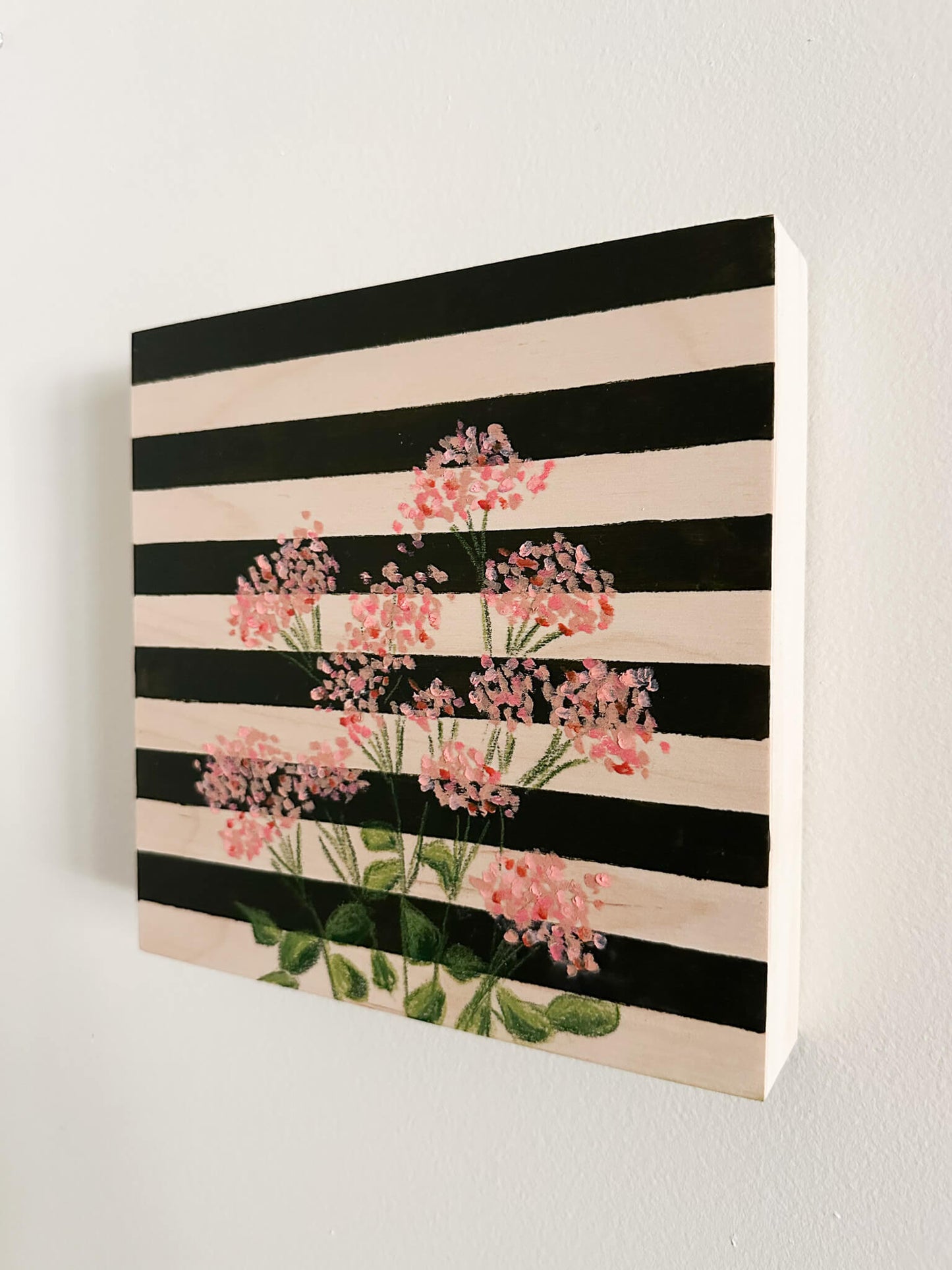 pink oil pastel florals on a very dark green and wood striped wood panel.