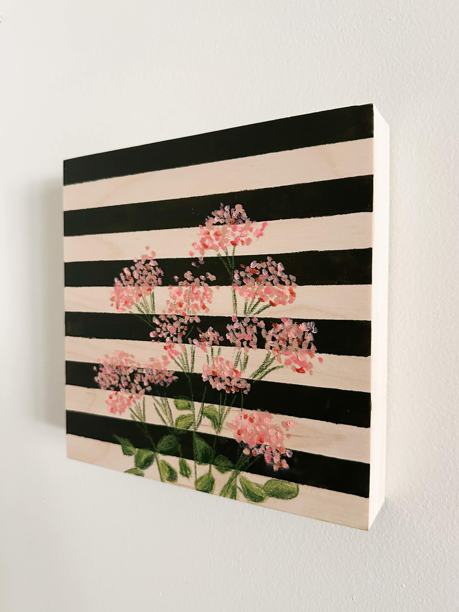 pink oil pastel florals on a very dark green and wood striped wood panel.