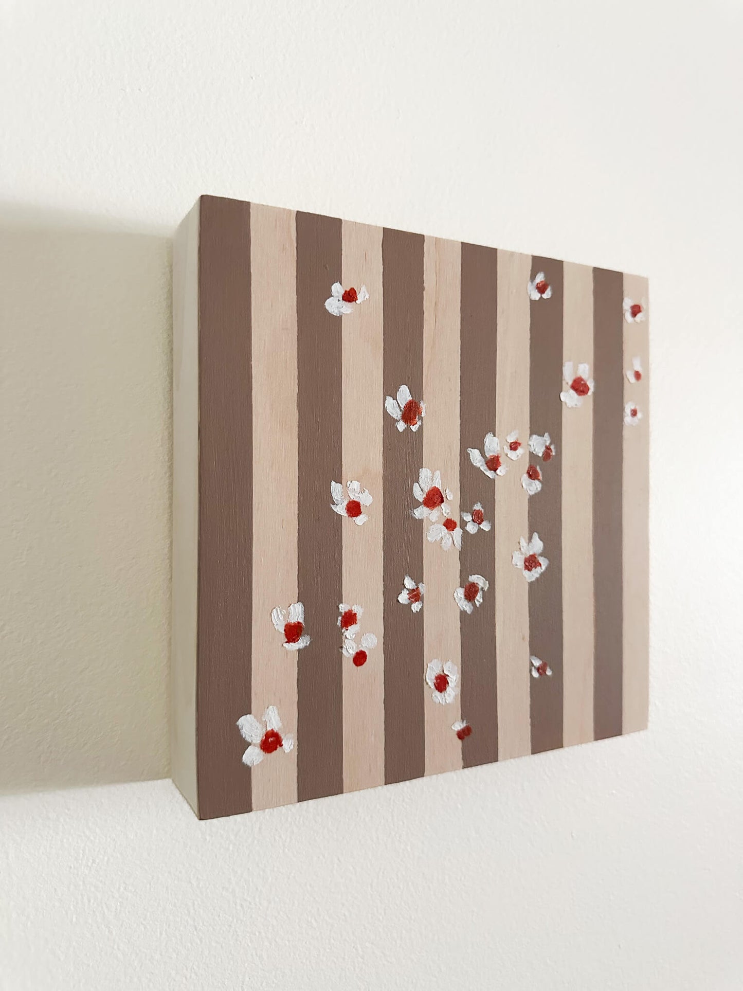 Pattern of white flowers with red centers on brown and wood striped wood panel