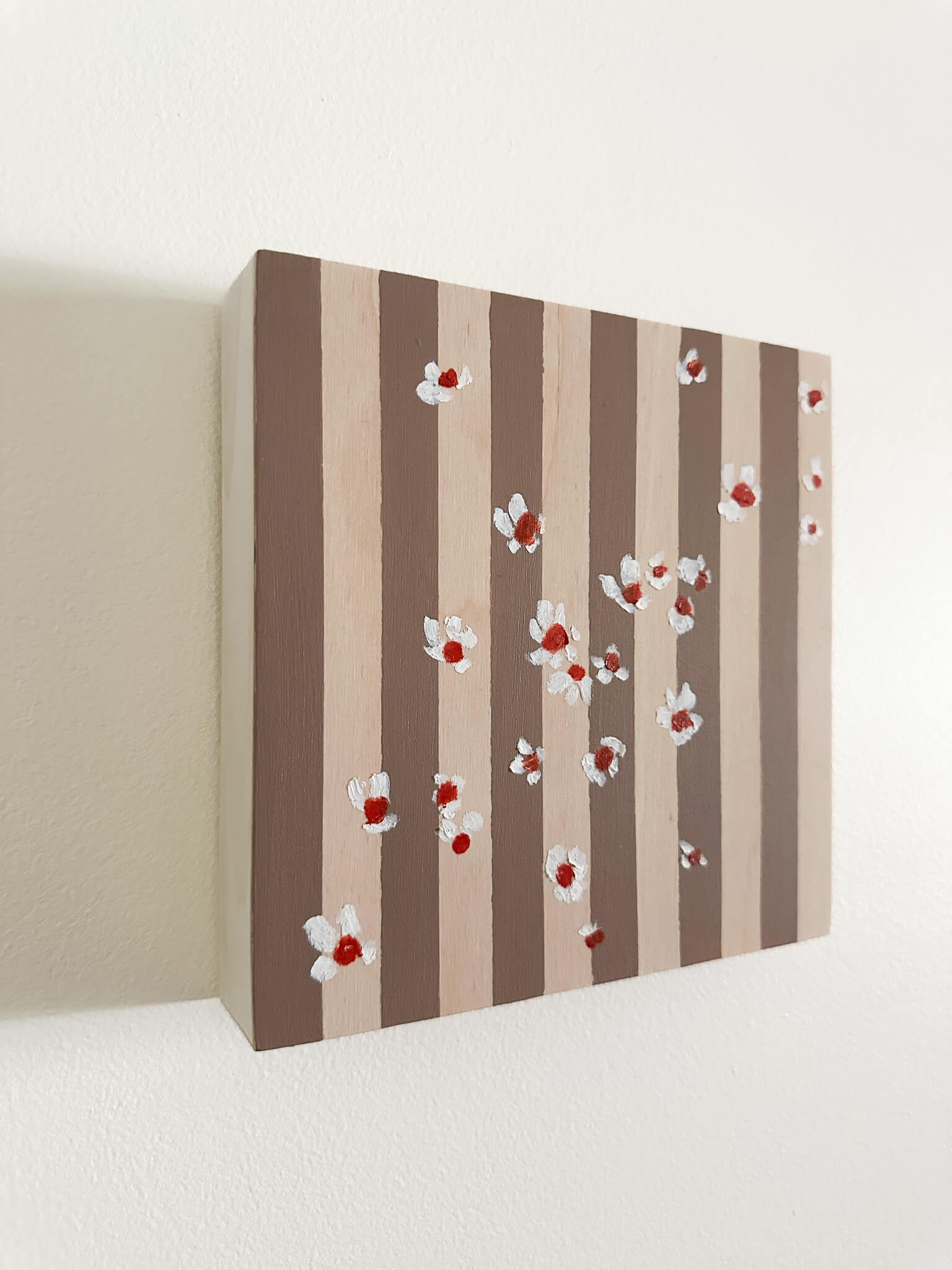 Pattern of white flowers with red centers on brown and wood striped wood panel