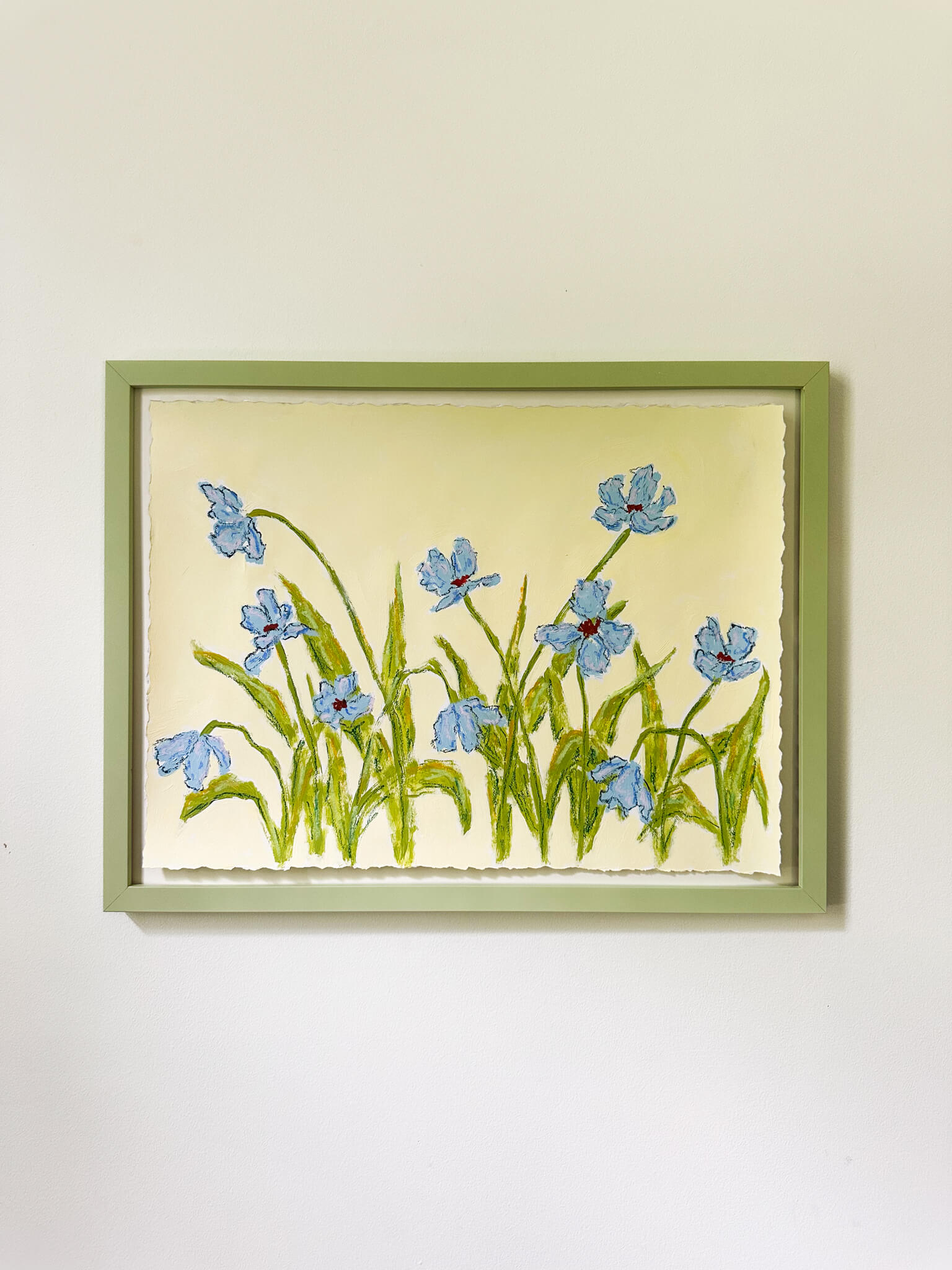 Framed artwork of blue flowers on a yellow background