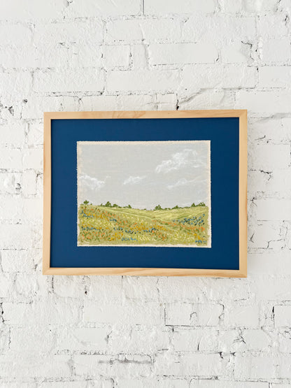 Framed landscape painting on a white brick wall