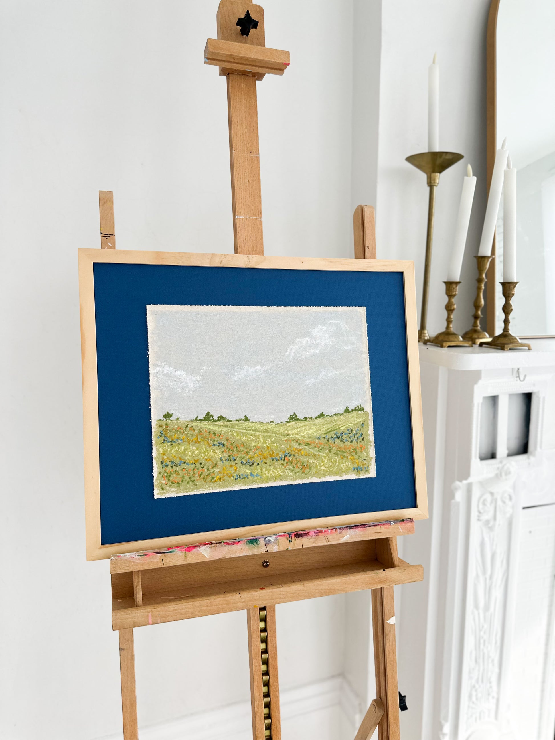 Art easel with a painting of a landscape on a white wall