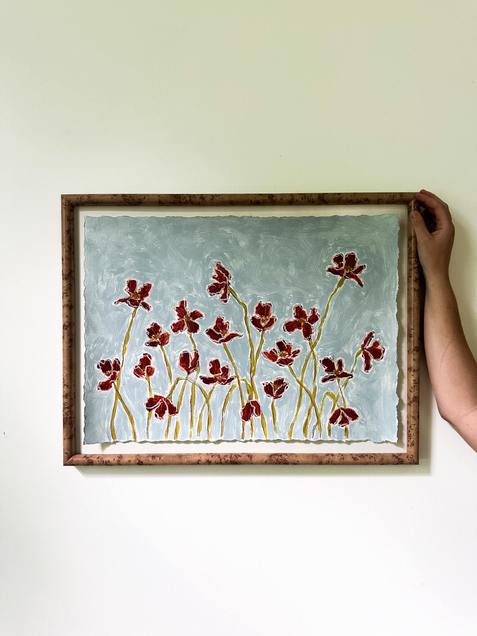 Framed artwork with red floral design on a light background
