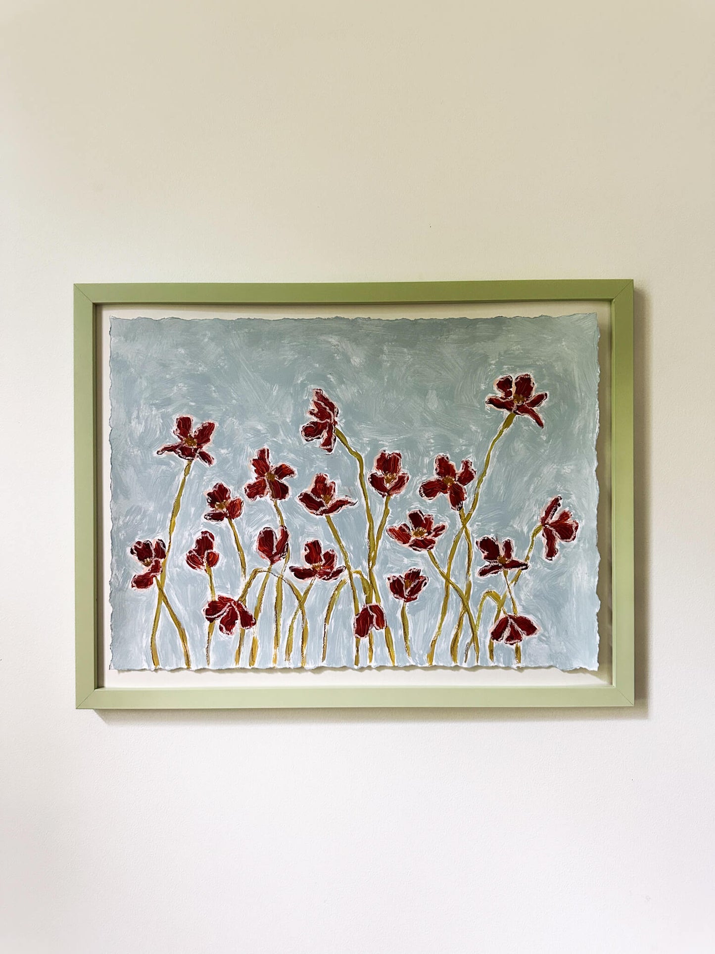 Framed artwork of red floral design on a light blue background