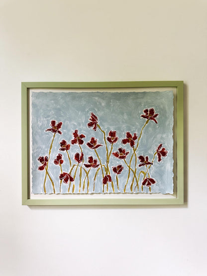 Framed artwork of red floral design on a light blue background