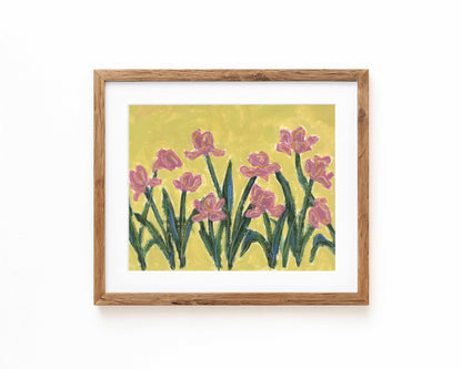 An art print of pink flowers on a green background framed in a natural wood frame and displayed against a white backdrop.