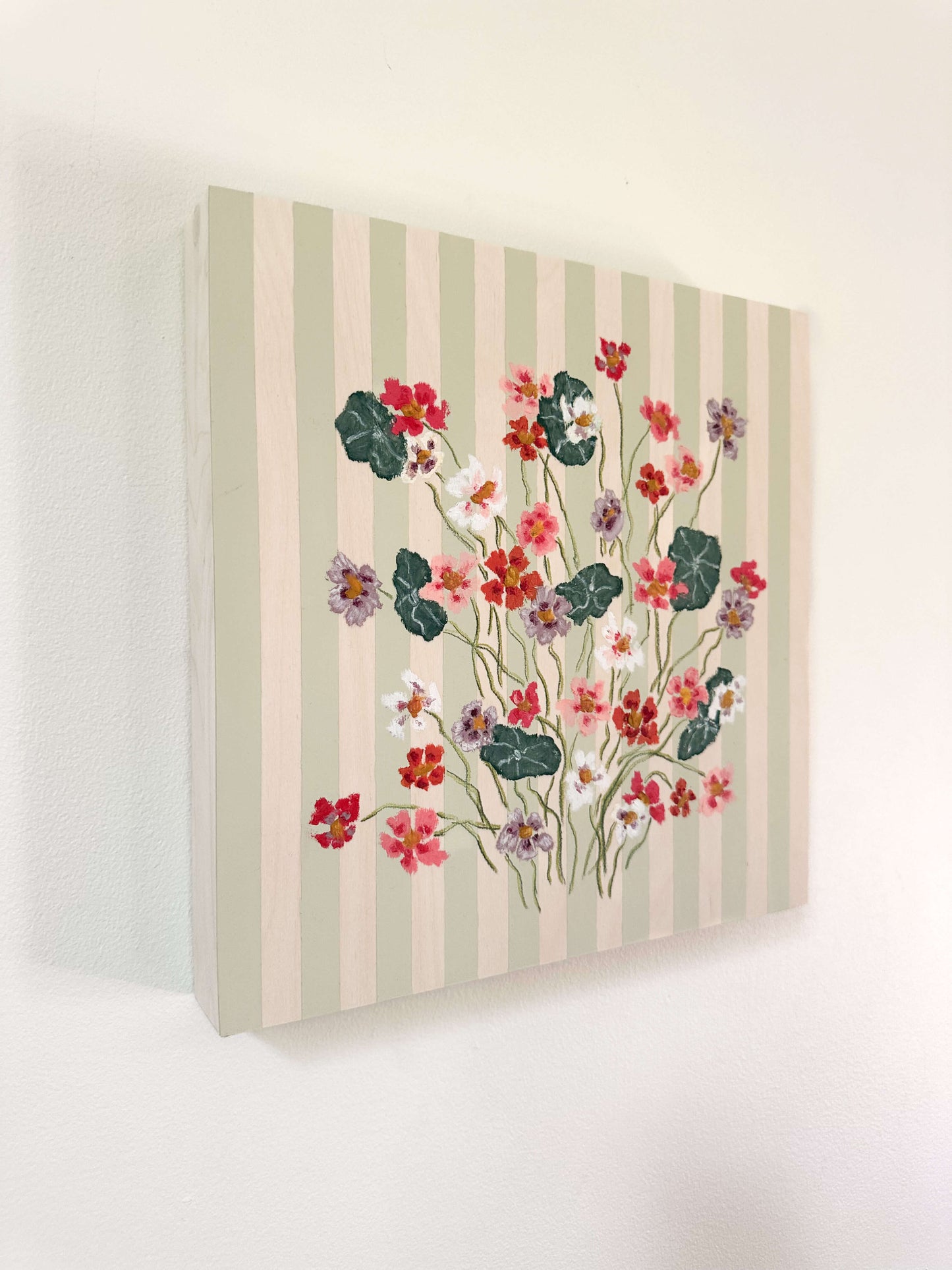 Floral painting on a striped canvas against a white wall