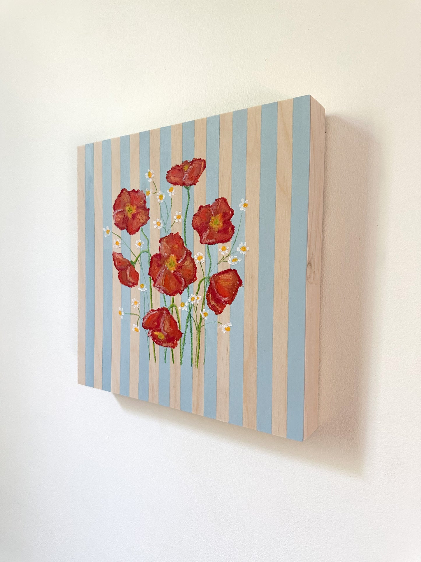 Canvas print with red flowers and blue stripes on a white wall