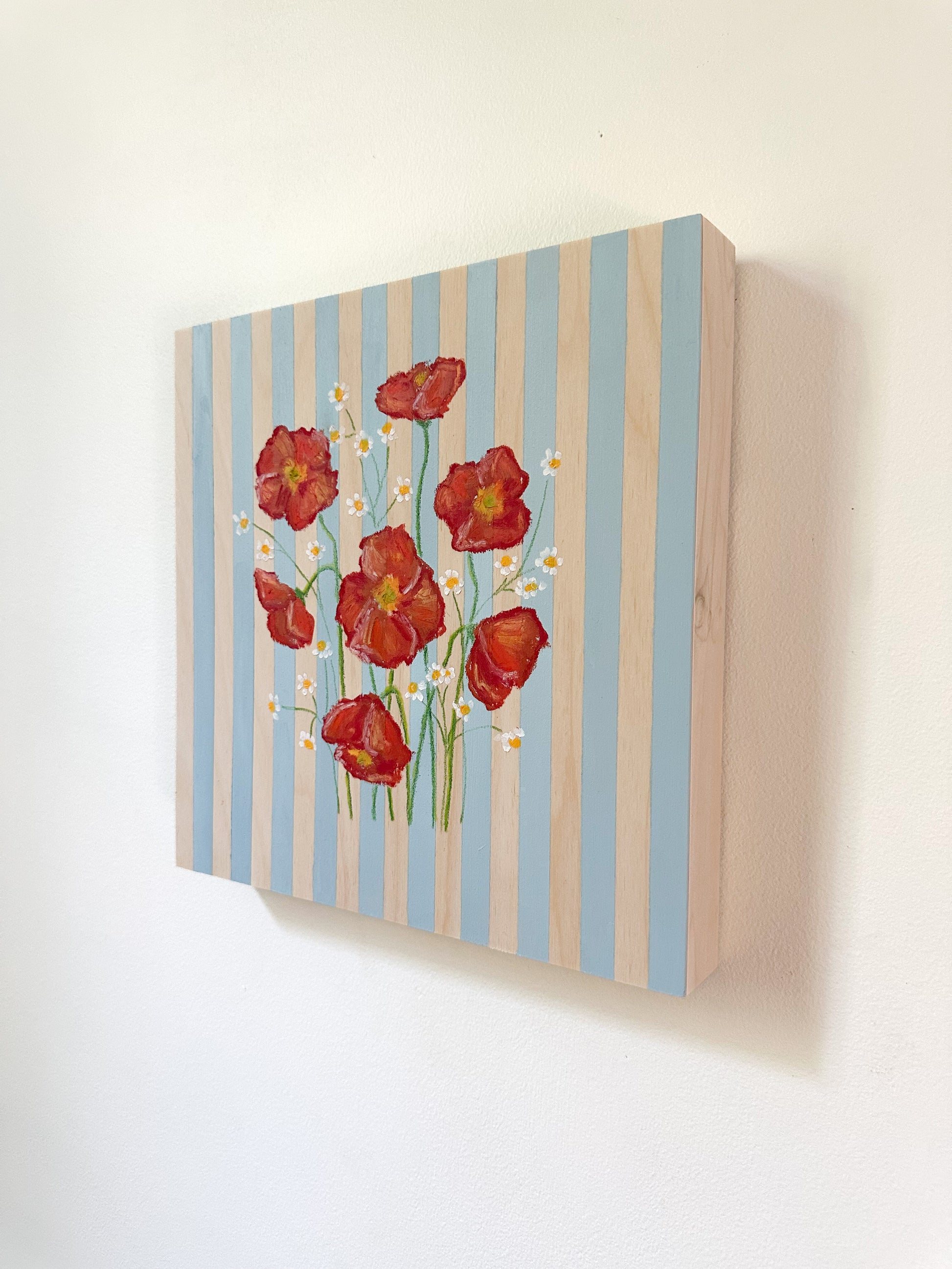 Canvas print with red flowers and blue stripes on a white wall