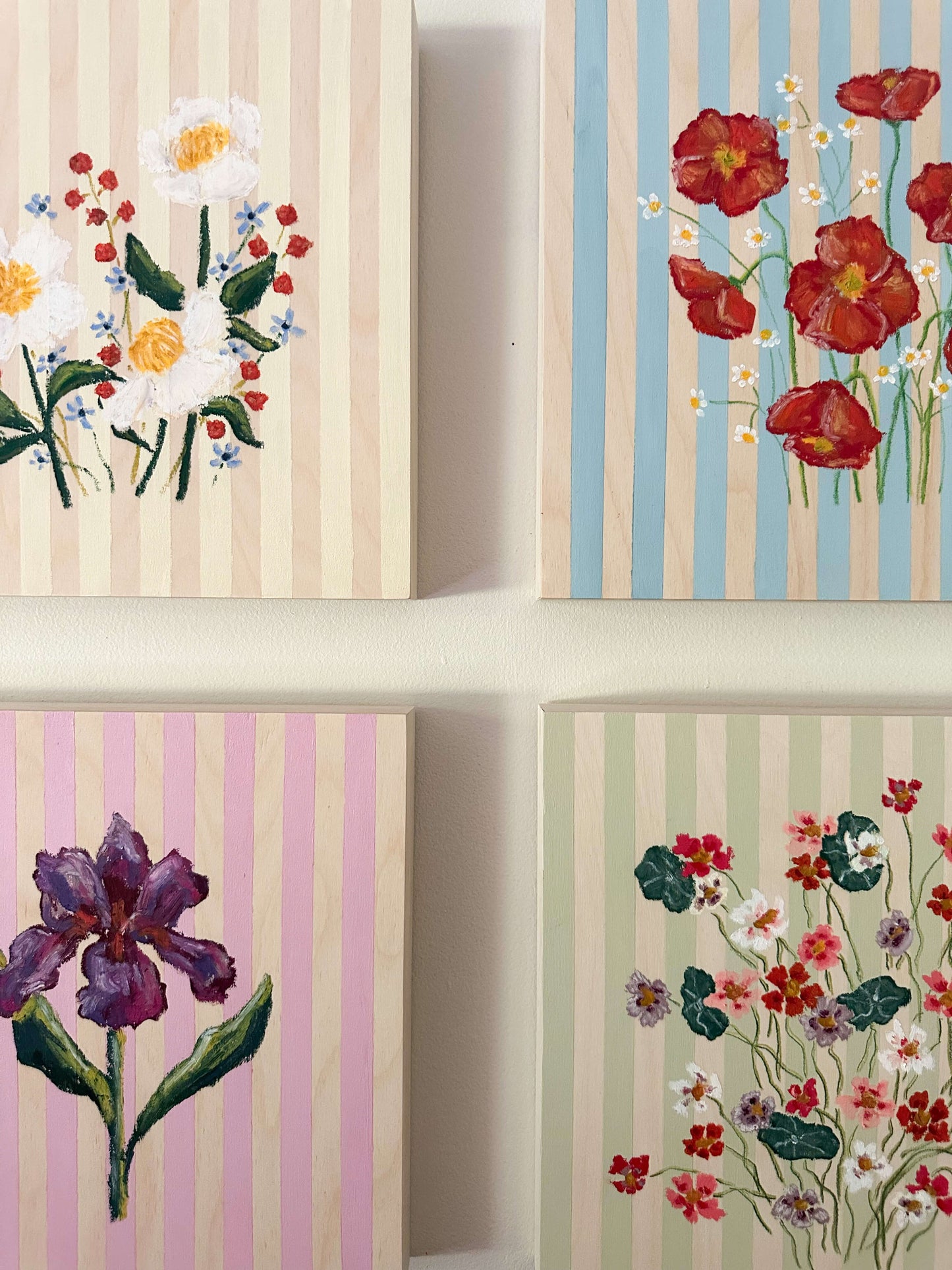 Four floral-themed wall art pieces with striped backgrounds