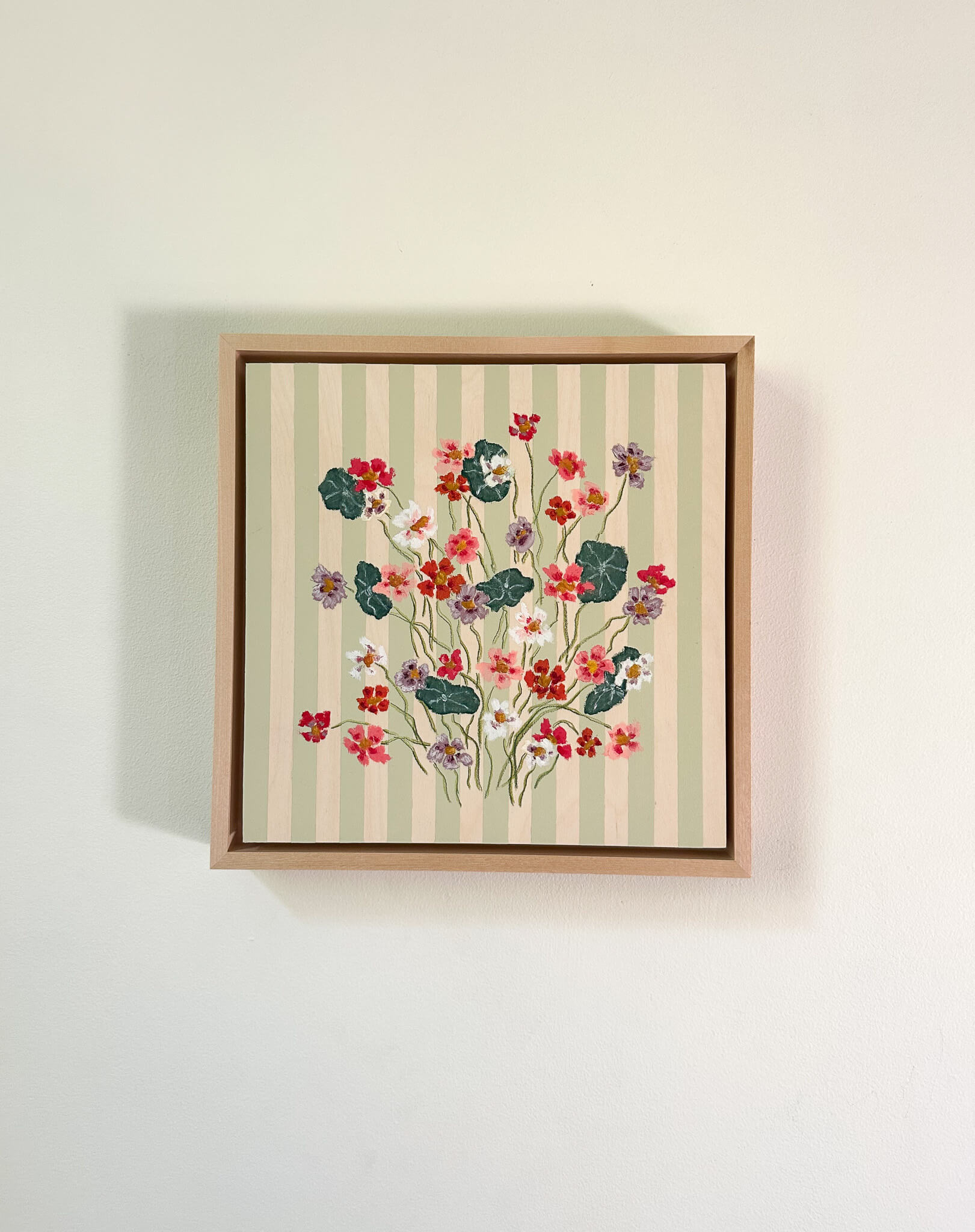Framed artwork with floral design on a striped background
