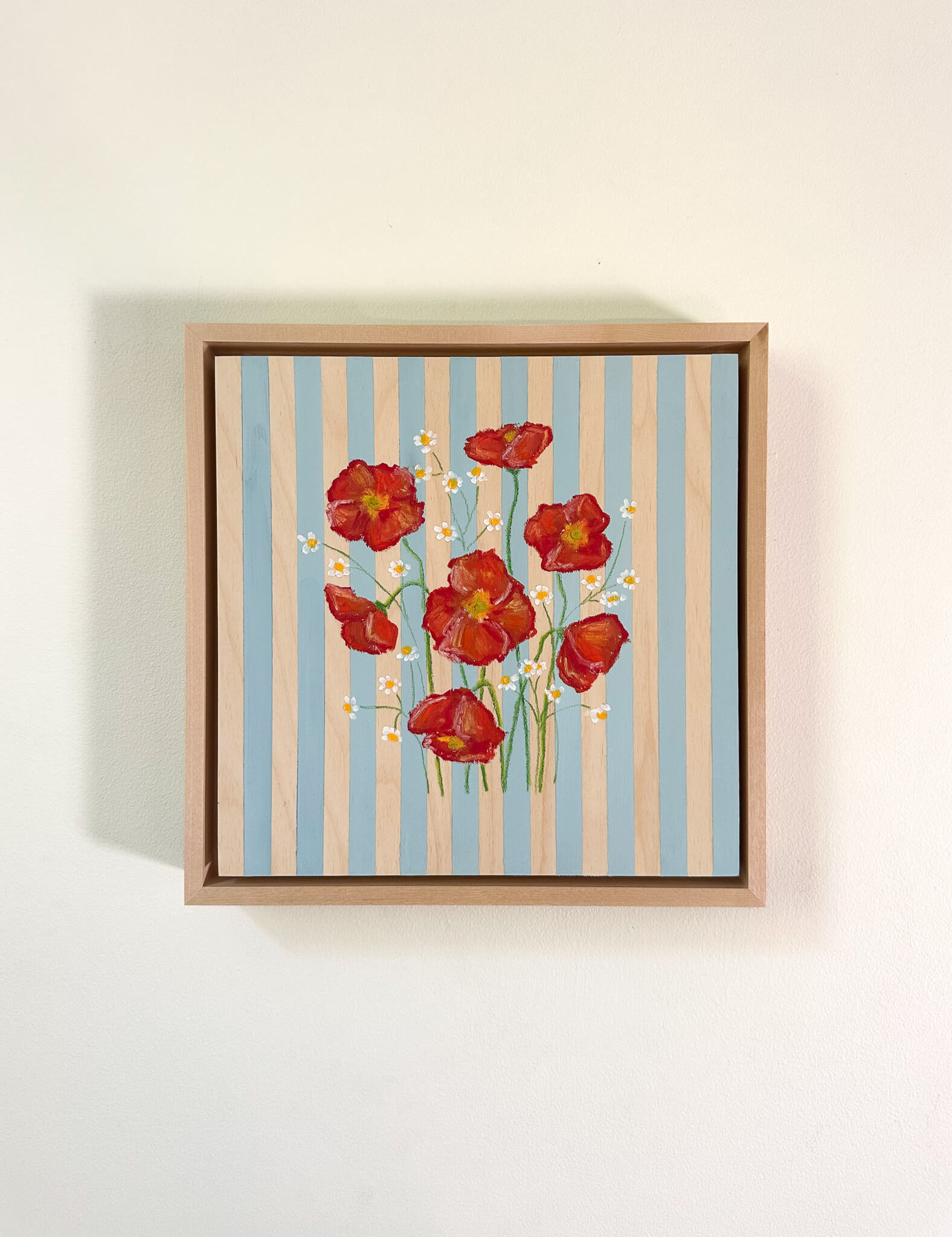 Framed artwork with red flowers on a striped background