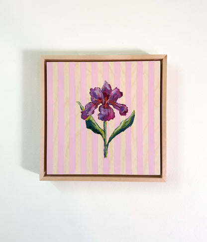 Framed artwork of a purple flower on a pink and yellow striped background