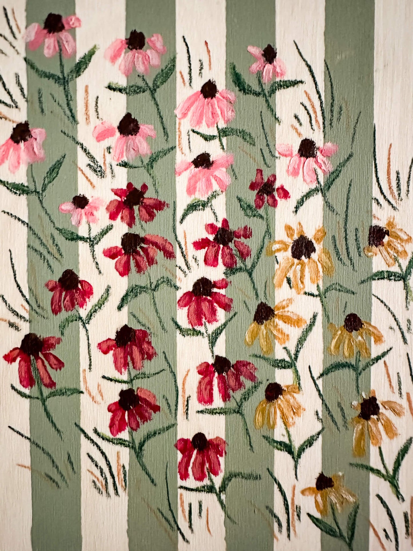 small pink, red, and yellow coneflowers on a green and wood striped wood panel.