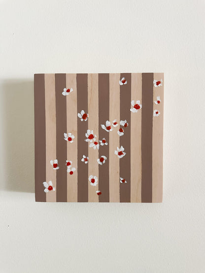 Pattern of white flowers with red centers on brown and wood striped wood panel