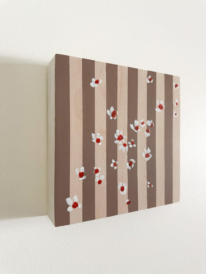 Pattern of white flowers with red centers on brown and wood striped wood panel