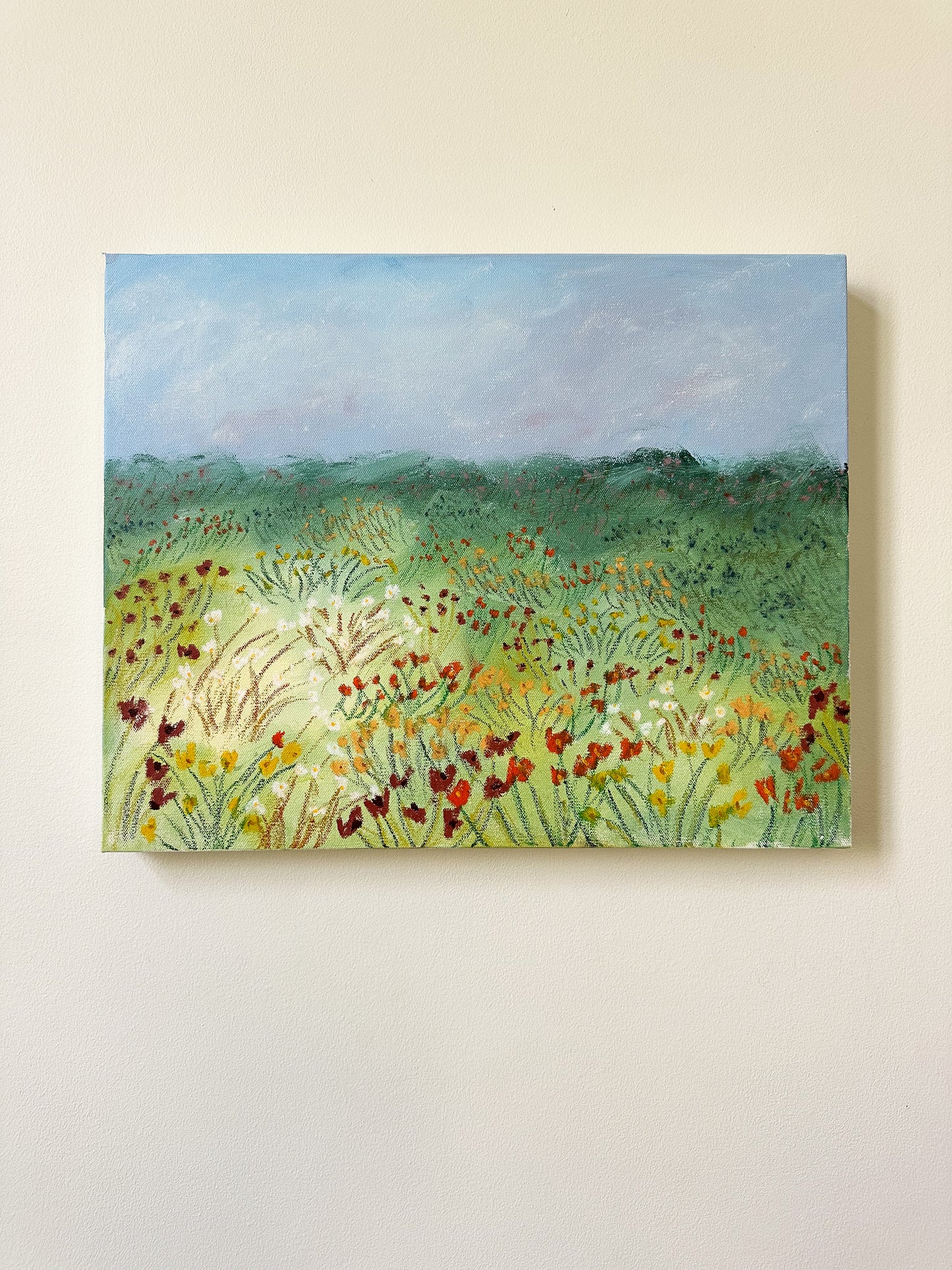 Painting of a field with flowers on a beige wall