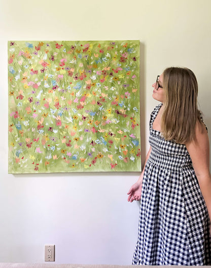 Woman in a checkered dress looking at a floral painting on a wall