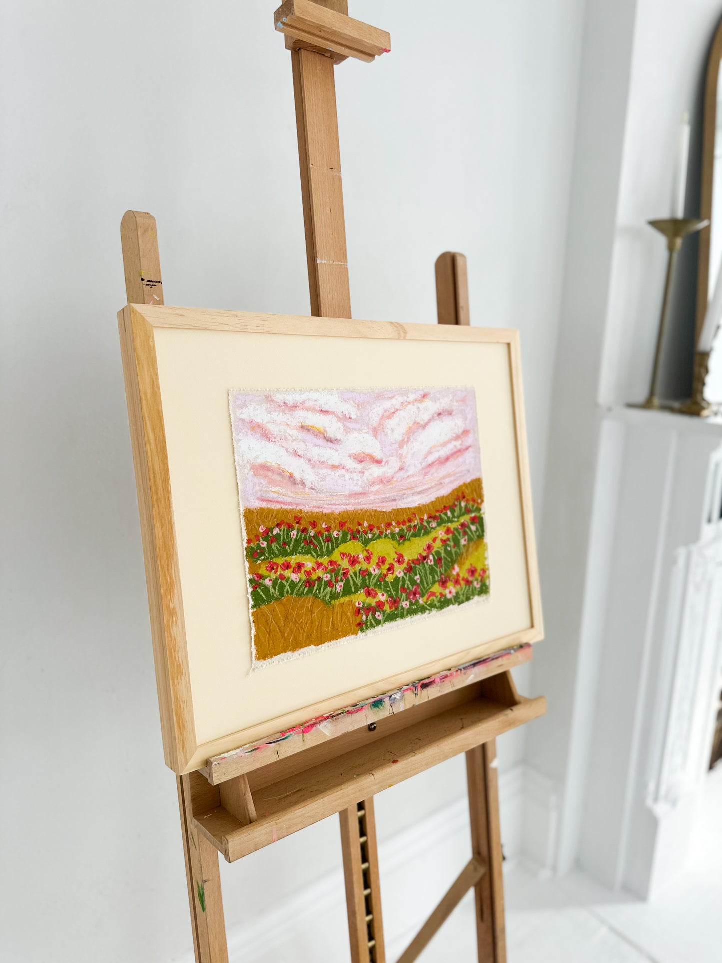 Painting of a landscape on an easel against a white wall