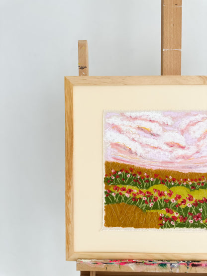 Embroidered landscape with flowers on a wooden easel against a white background
