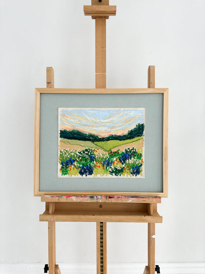 Painting of a landscape with flowers on an easel against a white background