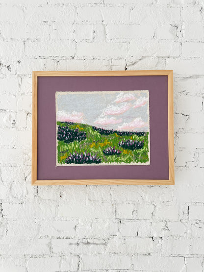 Framed landscape painting on a white brick wall