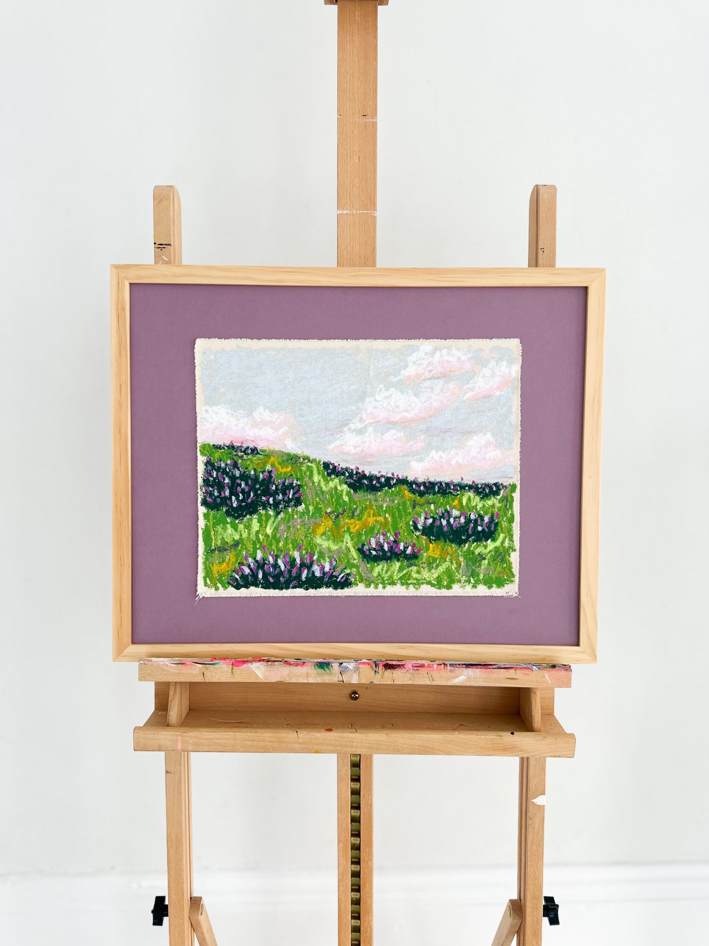 Painting of a landscape on an easel against a white background