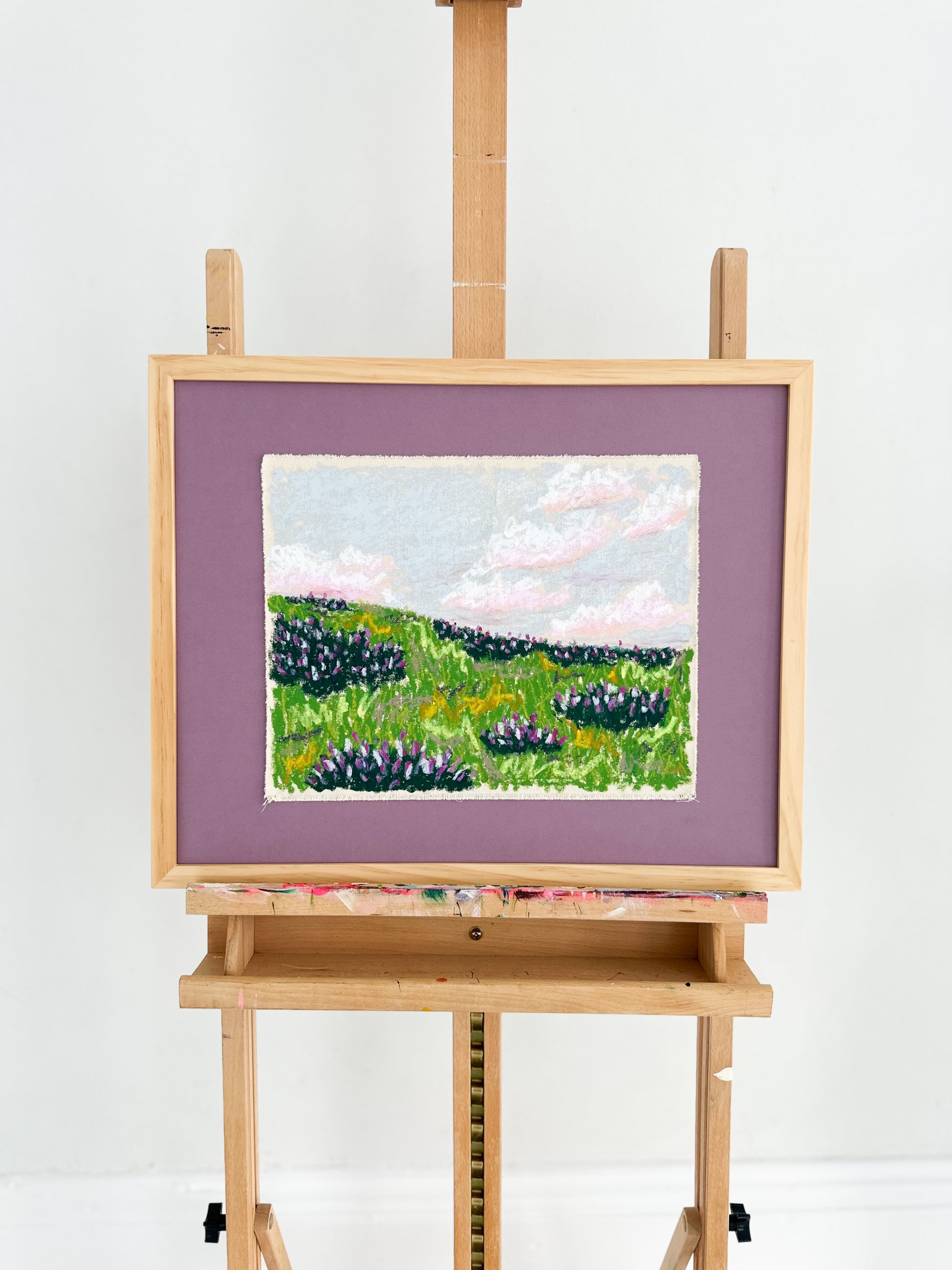 Painting of a landscape on an easel against a white background