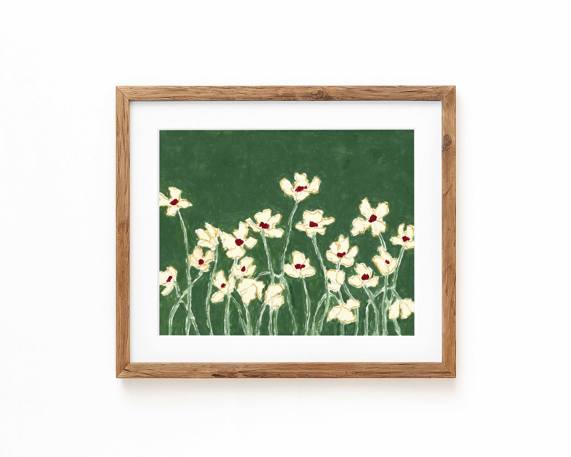 An art print of white flowers on a green background framed in a natural wood frame and displayed against a white backdrop.