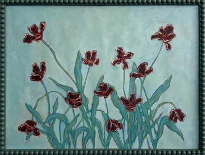 A painting of deep red flowers with teal leaves on a light teal background and framed in a dark teal bobbin frame. 