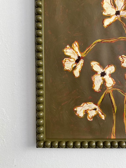 The corner of a painting of off white flowers with green stems  on a  thyme green background framed in a thyme green bobbin frame.