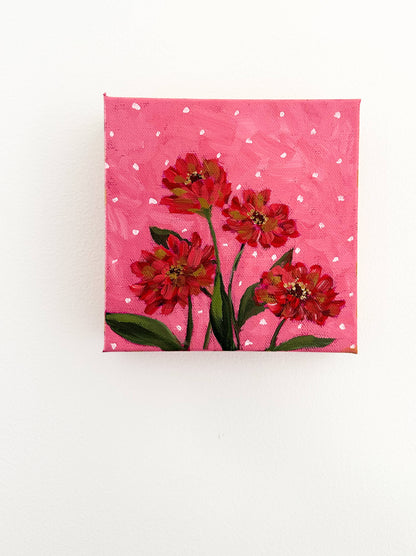 Small painting of red flowers on a pink polka dot background
