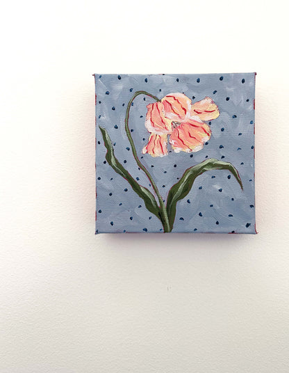 Small painting of a pink flower on a blue polka dot background