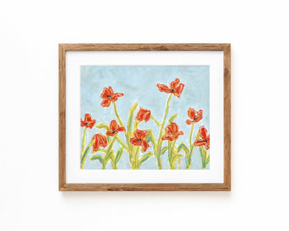 A print of orange flowers on a blue background framed in a wood frame.