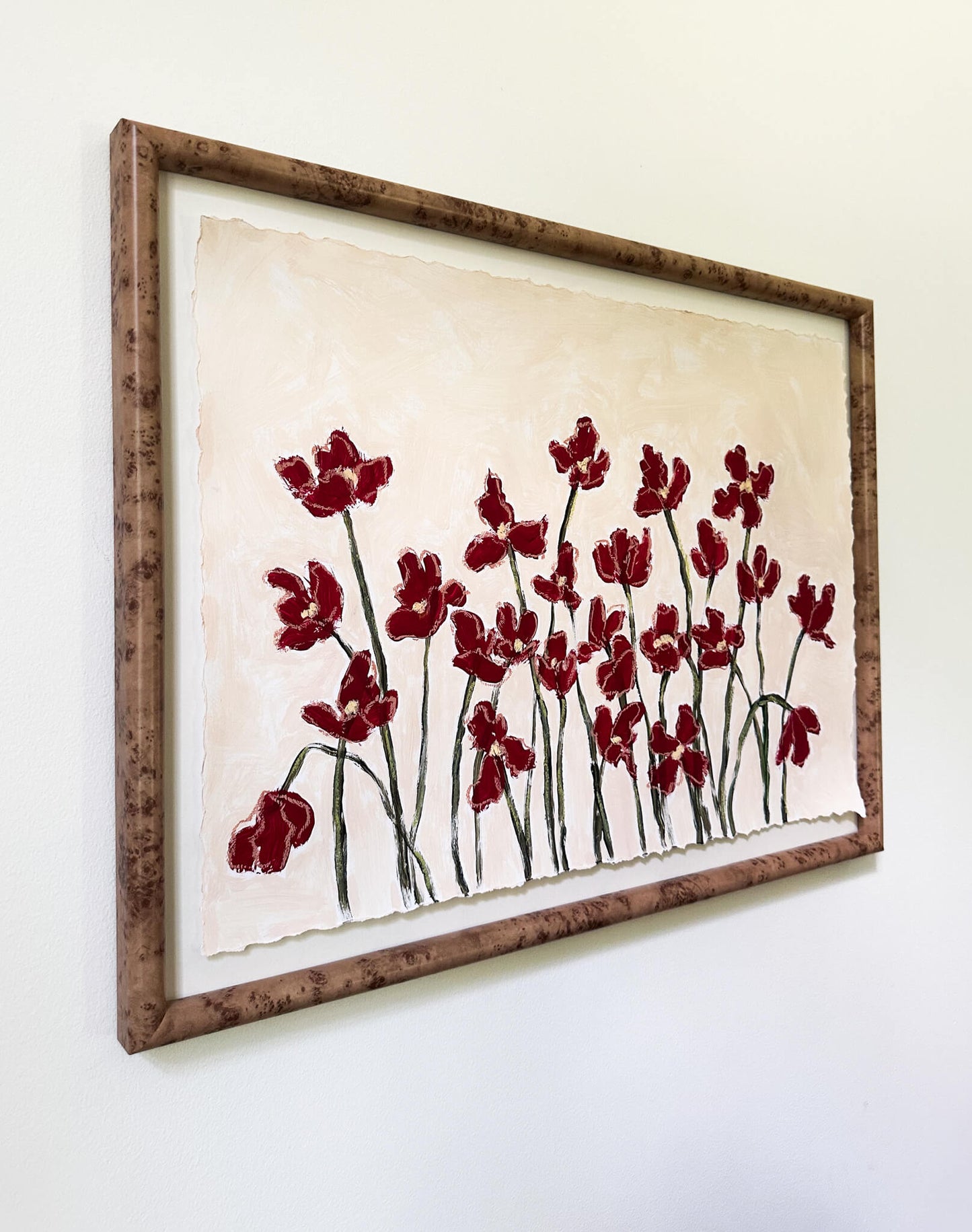 Framed artwork with red floral design on a white wall