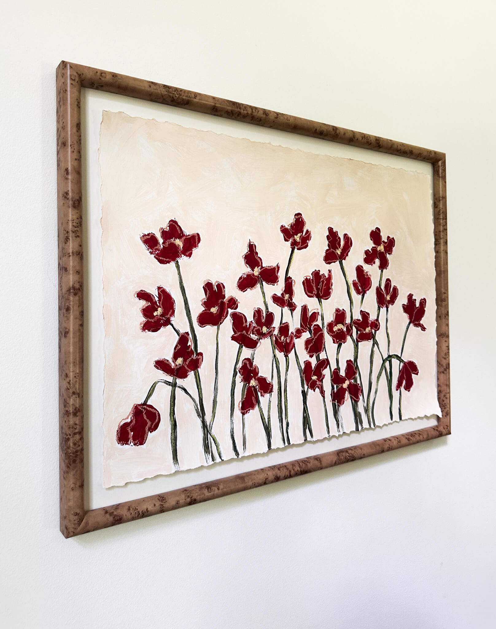 Framed artwork with red floral design on a white wall