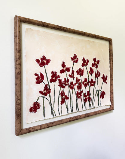 Framed artwork with red floral design on a white wall