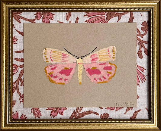a pink and yellow butterfly painting on tan paper, mounted on pink and tan floral fabric and framed in a gold frame.