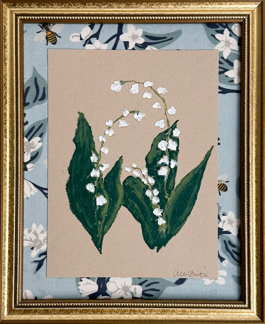 painting of lily of the valley flower on tan toned paper, framed in a gold frame and mounted on a blue floral fabric